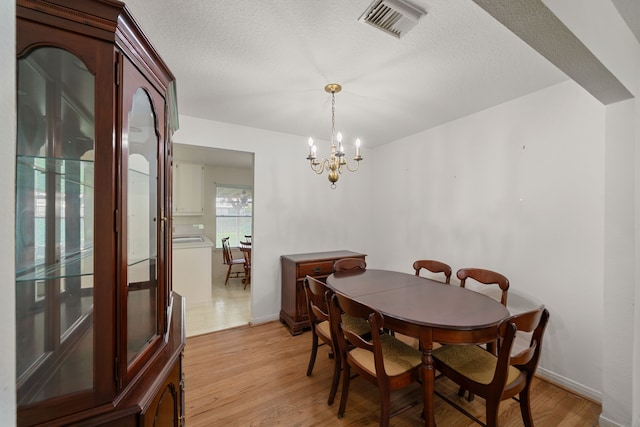 5006 Hazelton St, Houston, TX 77035 - dining area featuring light wood-style flooring, a chandelier, and a textured ceiling