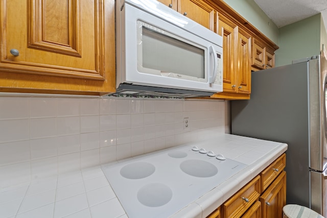 11614 Brighton Ln, Meadows Place, TX 77477 - kitchen with white appliances, tile counters, brown cabinets, and decorative backsplash