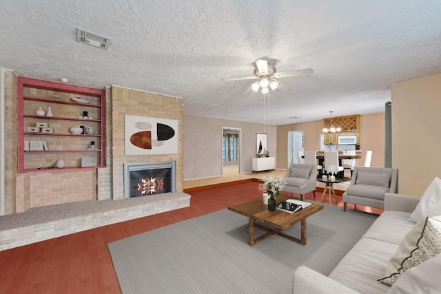 11614 Brighton Ln, Meadows Place, TX 77477 - living room featuring a ceiling fan, a textured ceiling, a brick fireplace, wood finished floors, and a chandelier