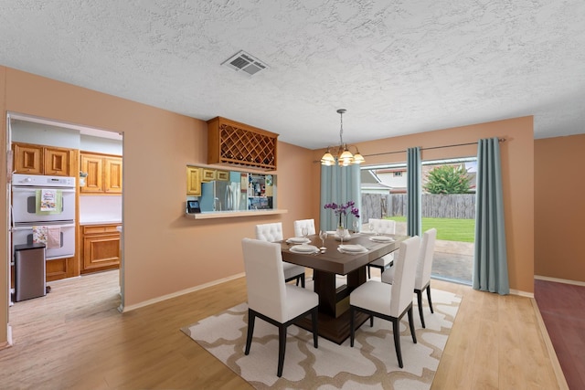 11614 Brighton Ln, Meadows Place, TX 77477 - dining area with a chandelier, light wood-type flooring, and a textured ceiling