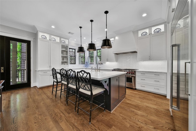 811 Byrne St, Houston, TX 77009 - kitchen with high end stainless steel range, custom range hood, light countertops, a kitchen island with sink, and a kitchen breakfast bar