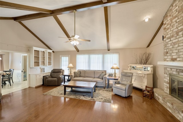 15402 Ripplestream, Houston, TX 77068 - living area featuring a ceiling fan, a fireplace, beam ceiling, wood finished floors, and high vaulted ceiling