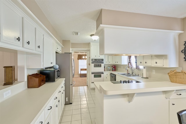 15402 Ripplestream, Houston, TX 77068 - kitchen featuring black appliances, a peninsula, plenty of natural light, light countertops, and a textured ceiling