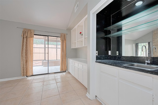 17207 Meadow Butte Dr, Houston, TX 77090 - kitchen featuring lofted ceiling, plenty of natural light, white cabinetry, light tile patterned floors, and dark stone counters