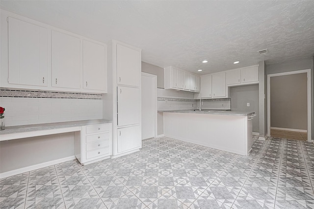 17207 Meadow Butte Dr, Houston, TX 77090 - kitchen featuring built in desk, light countertops, white cabinetry, a peninsula, and decorative backsplash