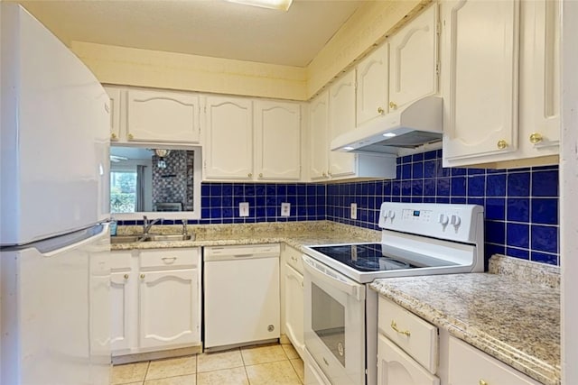 7840 Bateman Ln, Houston, TX 77088 - kitchen featuring white appliances, under cabinet range hood, light tile patterned floors, white cabinetry, and backsplash