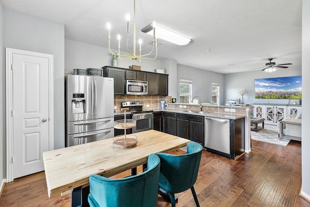 454 Fishhawk Way, Crosby, TX 77532 - kitchen with appliances with stainless steel finishes, a peninsula, a chandelier, dark wood-style floors, and tasteful backsplash