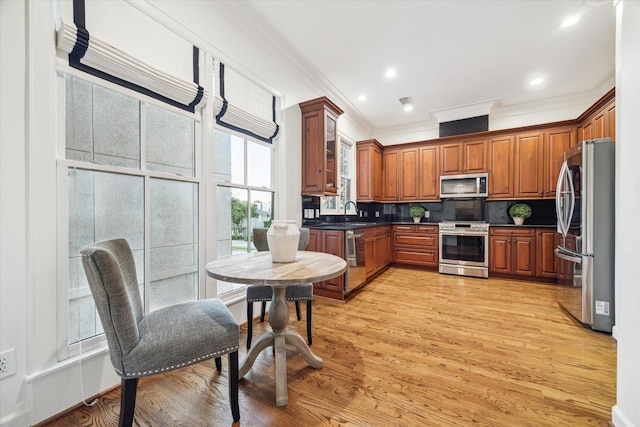 5200 Jackson St, Houston, TX 77004 - kitchen with appliances with stainless steel finishes, ornamental molding, dark countertops, brown cabinets, and light wood-style flooring