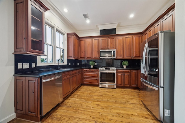 5200 Jackson St, Houston, TX 77004 - kitchen with appliances with stainless steel finishes, dark countertops, crown molding, light wood-type flooring, and backsplash