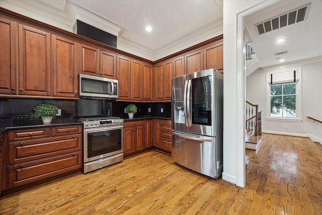5200 Jackson St, Houston, TX 77004 - kitchen featuring appliances with stainless steel finishes, dark countertops, backsplash, light wood-style floors, and crown molding