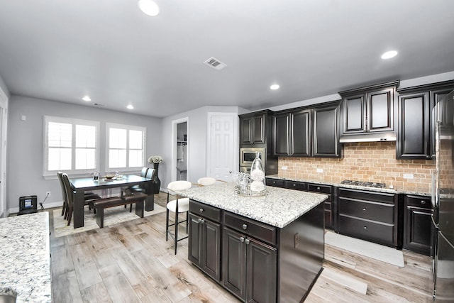 9003 Alps Peak Ct, Richmond, TX 77407 - kitchen with backsplash, a center island, appliances with stainless steel finishes, light stone countertops, and recessed lighting
