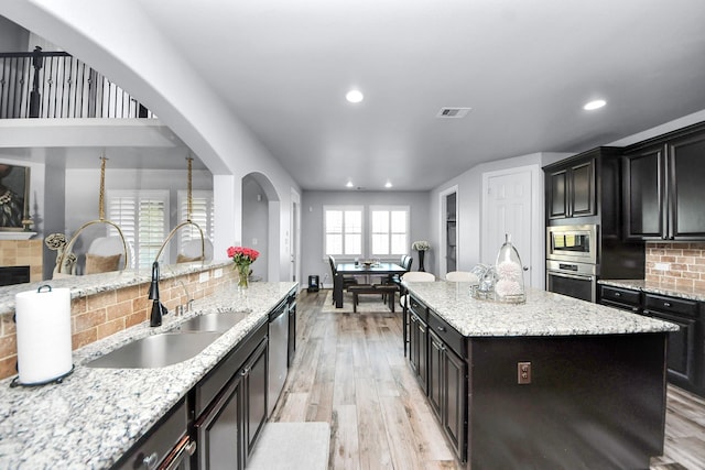 9003 Alps Peak Ct, Richmond, TX 77407 - kitchen with appliances with stainless steel finishes, recessed lighting, decorative backsplash, light wood-type flooring, and a center island