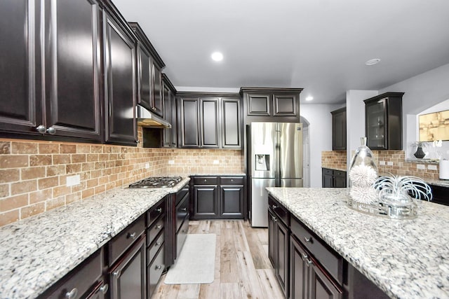 9003 Alps Peak Ct, Richmond, TX 77407 - kitchen featuring appliances with stainless steel finishes, decorative backsplash, light stone countertops, light wood finished floors, and recessed lighting