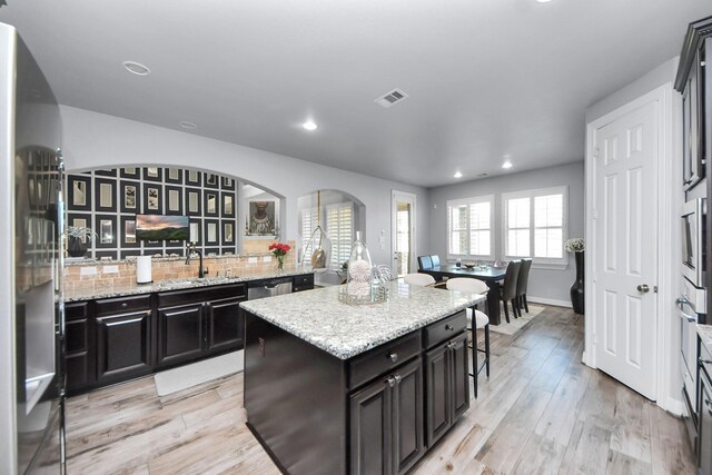 9003 Alps Peak Ct, Richmond, TX 77407 - kitchen with arched walkways, appliances with stainless steel finishes, recessed lighting, light wood finished floors, and a kitchen island