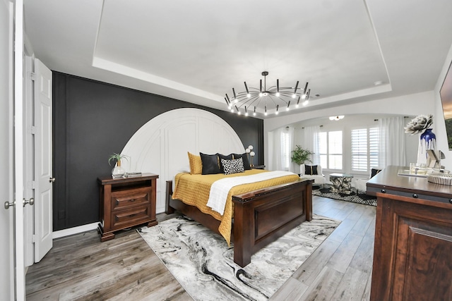 9003 Alps Peak Ct, Richmond, TX 77407 - bedroom with a raised ceiling, wood finished floors, arched walkways, and a chandelier