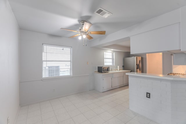 3906 Antoine Dr, Houston, TX 77092 - kitchen with appliances with stainless steel finishes, light countertops, a peninsula, a ceiling fan, and white cabinetry