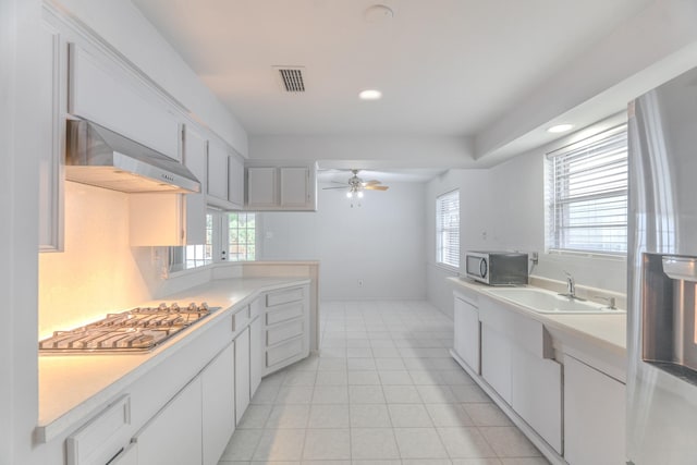 3906 Antoine Dr, Houston, TX 77092 - kitchen featuring appliances with stainless steel finishes, wall chimney exhaust hood, light countertops, ceiling fan, and white cabinets