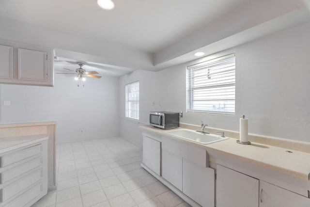 3906 Antoine Dr, Houston, TX 77092 - kitchen with stainless steel microwave, light countertops, a ceiling fan, light tile patterned flooring, and white cabinets