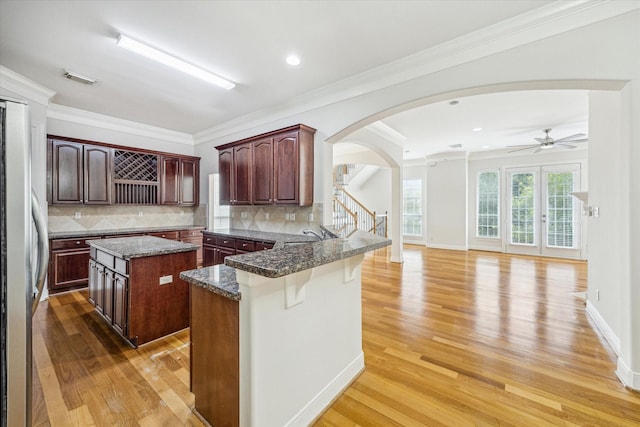 1316 Birdsall St, Houston, TX 77007 - kitchen with freestanding refrigerator, ceiling fan, arched walkways, light wood finished floors, and a peninsula