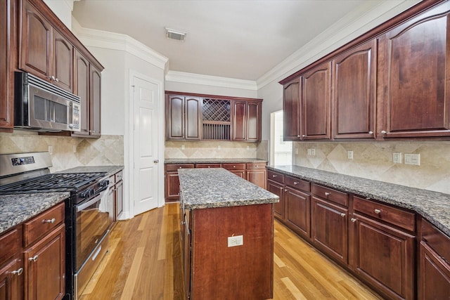 1316 Birdsall St, Houston, TX 77007 - kitchen with stainless steel appliances, light wood-type flooring, a center island, ornamental molding, and backsplash