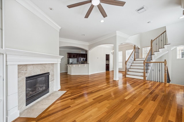 1316 Birdsall St, Houston, TX 77007 - unfurnished living room with a ceiling fan, arched walkways, ornamental molding, light wood-style floors, and a fireplace