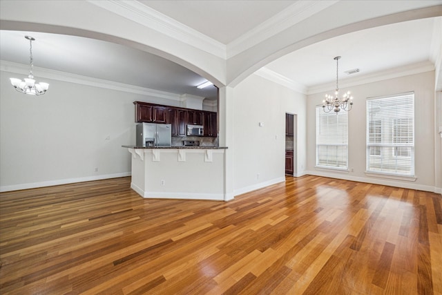 1316 Birdsall St, Houston, TX 77007 - unfurnished living room featuring a chandelier, light wood finished floors, ornamental molding, and arched walkways