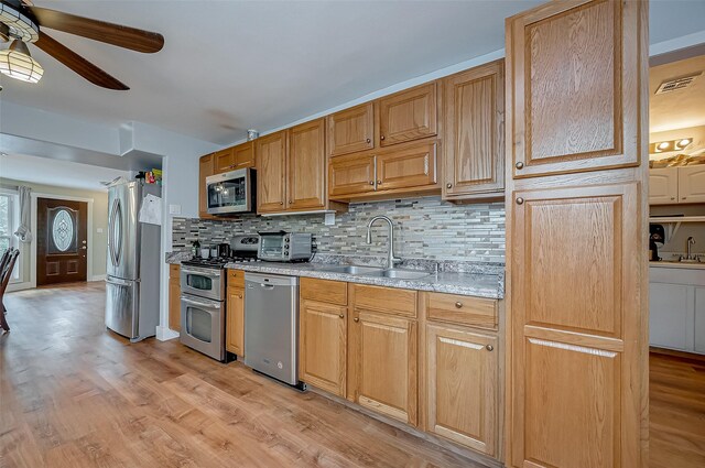 22914 Whittaker Way, Spring, TX 77373 - kitchen featuring stainless steel appliances, ceiling fan, decorative backsplash, and light wood-type flooring
