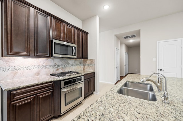 5107 Preserve Park Dr, Spring, TX 77389 - kitchen with stainless steel appliances, backsplash, light stone counters, dark brown cabinets, and light tile patterned floors