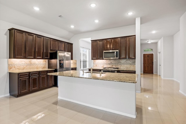 5107 Preserve Park Dr, Spring, TX 77389 - kitchen with appliances with stainless steel finishes, dark brown cabinets, recessed lighting, decorative backsplash, and light stone counters