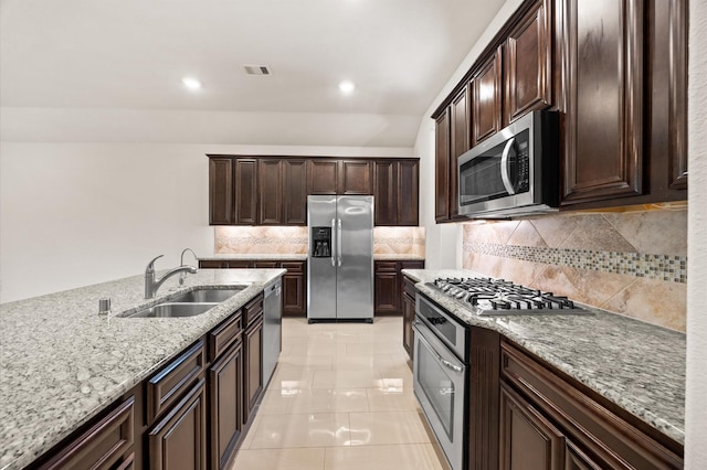 5107 Preserve Park Dr, Spring, TX 77389 - kitchen featuring appliances with stainless steel finishes, light stone counters, decorative backsplash, dark brown cabinets, and recessed lighting