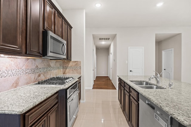 5107 Preserve Park Dr, Spring, TX 77389 - kitchen featuring appliances with stainless steel finishes, decorative backsplash, dark brown cabinets, light stone counters, and recessed lighting
