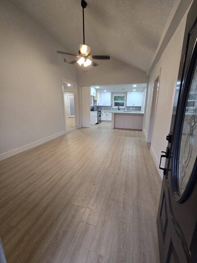 5326 Dewberry St, Houston, TX 77021 - unfurnished living room with vaulted ceiling, a textured ceiling, light wood finished floors, and a ceiling fan
