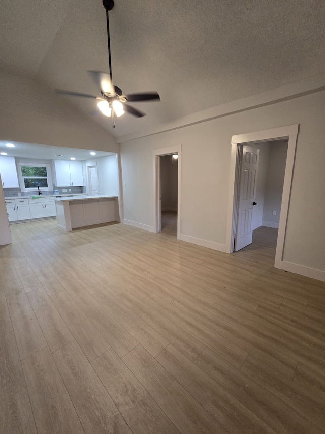 5326 Dewberry St, Houston, TX 77021 - unfurnished living room with a ceiling fan, light wood-style flooring, a textured ceiling, and vaulted ceiling