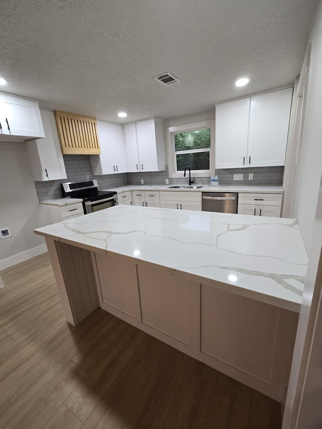 5326 Dewberry St, Houston, TX 77021 - kitchen with stainless steel appliances, ventilation hood, wood finished floors, light stone counters, and backsplash