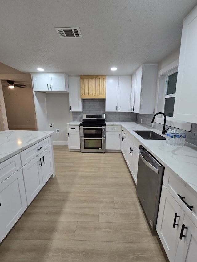 5326 Dewberry St, Houston, TX 77021 - kitchen with stainless steel appliances, light stone countertops, a textured ceiling, white cabinets, and backsplash