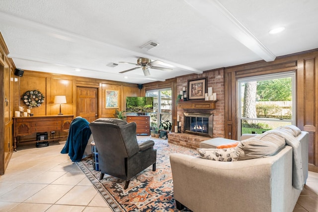9611 Stockport Dr, Spring, TX 77379 - living room featuring light tile patterned floors, a fireplace, wood walls, a ceiling fan, and a textured ceiling