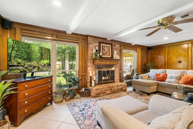 9611 Stockport Dr, Spring, TX 77379 - living room with light tile patterned floors, beamed ceiling, a textured ceiling, a brick fireplace, and ceiling fan