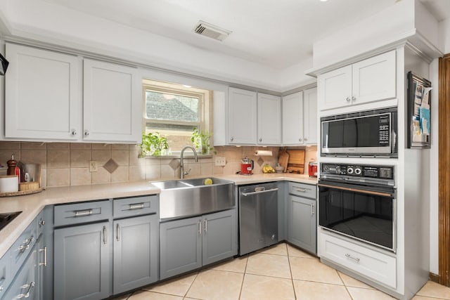 9611 Stockport Dr, Spring, TX 77379 - kitchen featuring stainless steel appliances, light tile patterned floors, light countertops, and gray cabinetry