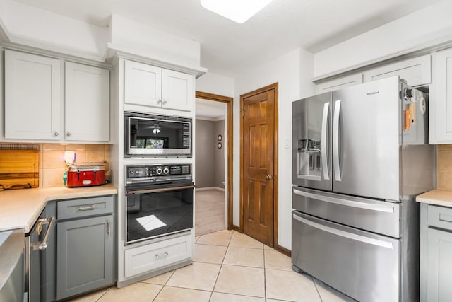 9611 Stockport Dr, Spring, TX 77379 - kitchen with appliances with stainless steel finishes, decorative backsplash, gray cabinets, light countertops, and light tile patterned floors