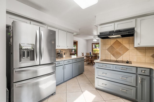 9611 Stockport Dr, Spring, TX 77379 - kitchen with stainless steel refrigerator with ice dispenser, under cabinet range hood, black electric cooktop, tasteful backsplash, and gray cabinetry
