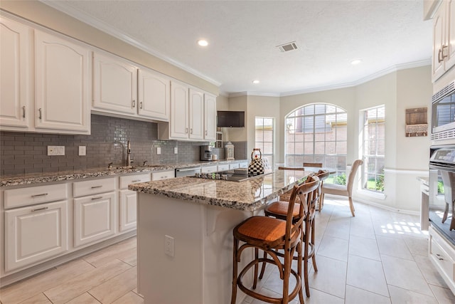 1907 Garden Fern Ct, Houston, TX 77062 - kitchen featuring appliances with stainless steel finishes, a kitchen bar, a kitchen island, light stone counters, and backsplash
