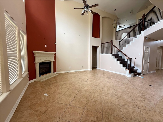 12503 Pepper Creek Ln, Pearland, TX 77584 - unfurnished living room with ceiling fan, a high ceiling, a glass covered fireplace, arched walkways, and tile patterned floors