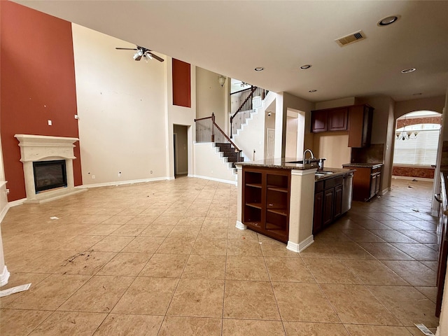 12503 Pepper Creek Ln, Pearland, TX 77584 - kitchen with ceiling fan, light tile patterned floors, open shelves, arched walkways, and a center island with sink