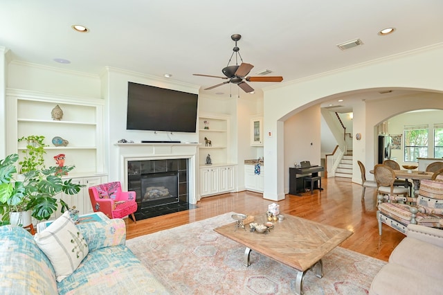 1307 W Bell St, Houston, TX 77019 - living room featuring stairs, arched walkways, a ceiling fan, ornamental molding, and built in features