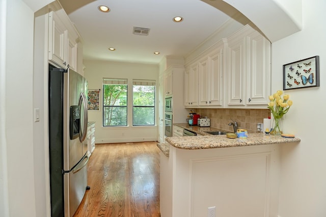 1307 W Bell St, Houston, TX 77019 - kitchen featuring appliances with stainless steel finishes, light wood finished floors, decorative backsplash, light stone countertops, and recessed lighting
