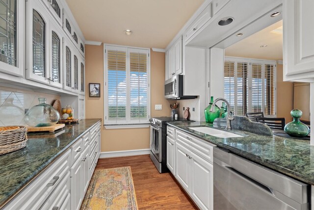 14655 Champion Forest Dr Unit 1704, Houston, TX 77069 - kitchen featuring appliances with stainless steel finishes, light wood-style floors, white cabinetry, glass insert cabinets, and dark stone countertops