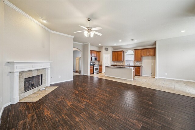 20779 Oakhurst Meadows Dr, Porter, TX 77365 - unfurnished living room with arched walkways, a ceiling fan, crown molding, recessed lighting, and a tile fireplace