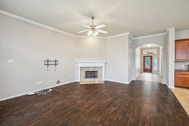 20779 Oakhurst Meadows Dr, Porter, TX 77365 - unfurnished living room with arched walkways, ceiling fan, wood finished floors, a tiled fireplace, and crown molding