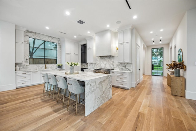 2220 Pelham Dr, Houston, TX 77019 - kitchen with a center island, white cabinetry, light wood-style floors, decorative backsplash, and recessed lighting
