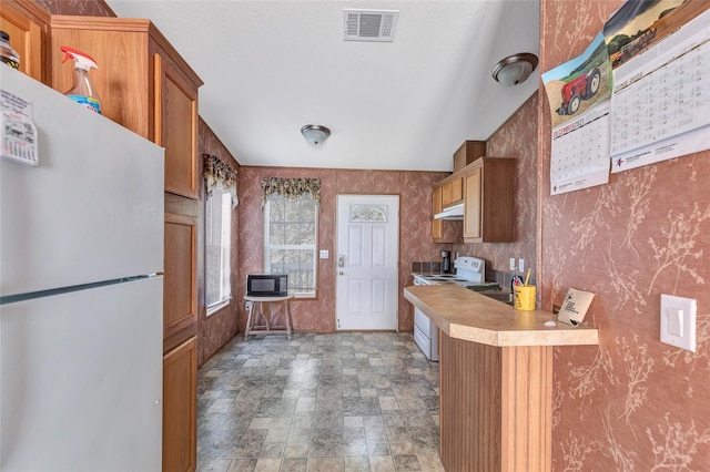 637 Troy St, Anahuac, TX 77514 - kitchen with white appliances, light countertops, wallpapered walls, stone finish floors, and brown cabinets